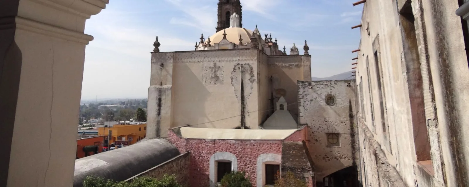 El templo de San Francisco Javier de Tepotzotlán visto desde el jardín del Museo Nacional del Virreinato, con su cúpula y su torre sobre los muros del colegio