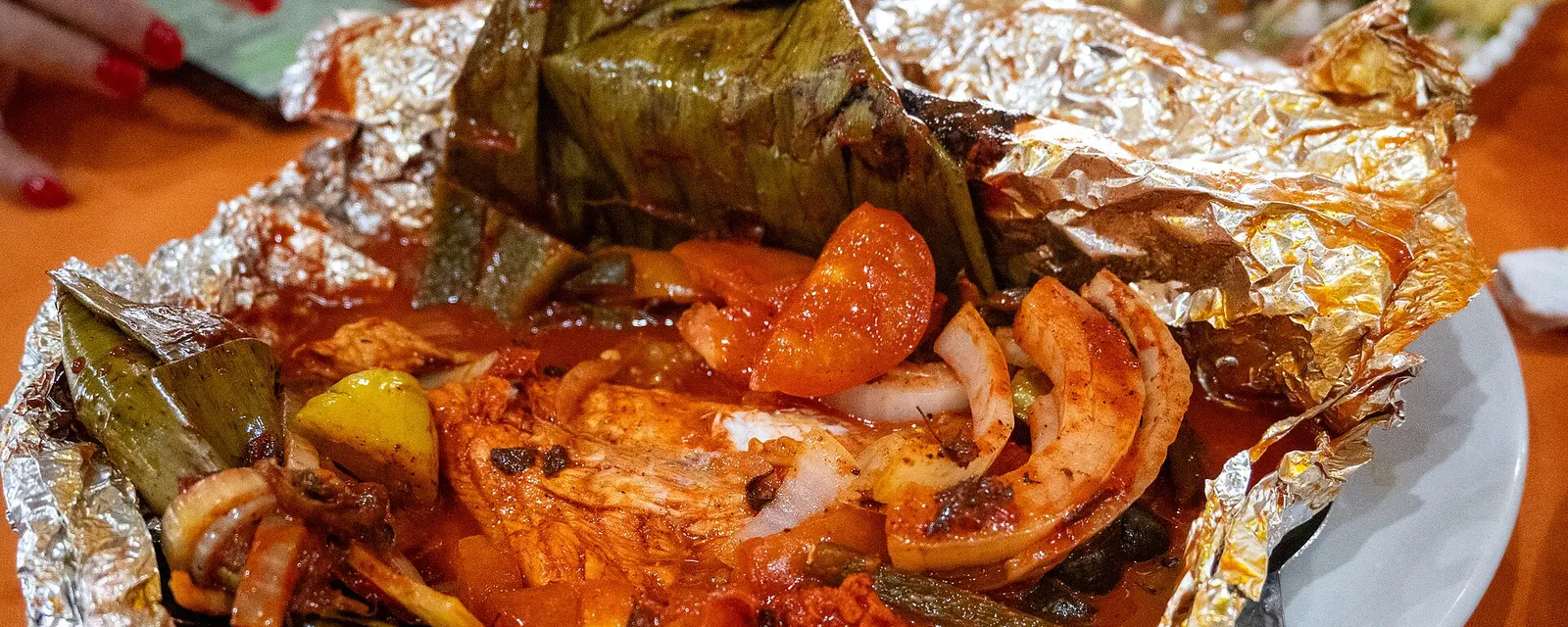 Pescado tikin-xic envuelto en hoja de plátano con salsa de achiote, cebolla y chile