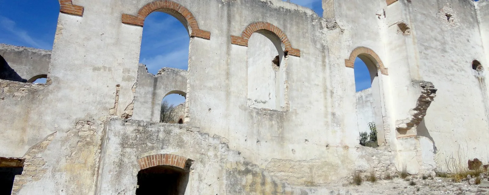 Las ruinas de la hacienda de beneficio de la mina Cinco Señores en Mineral de Pozos: muros sin techo con arcos de ladrillo abiertos al cielo