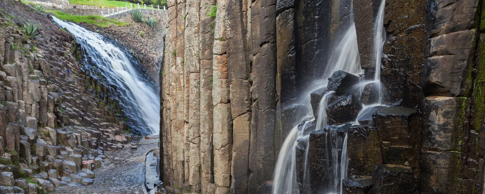 Las columnas de basalto de los Prismas Basálticos de Huasca vistas de frente, con dos caídas de agua descolgándose por la pared de roca