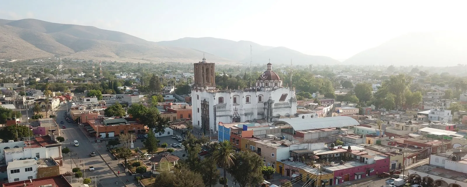 Zimapán desde el aire: el templo de San Juan Bautista con su torre y cúpula en medio del caserío, y los cerros de la sierra al fondo