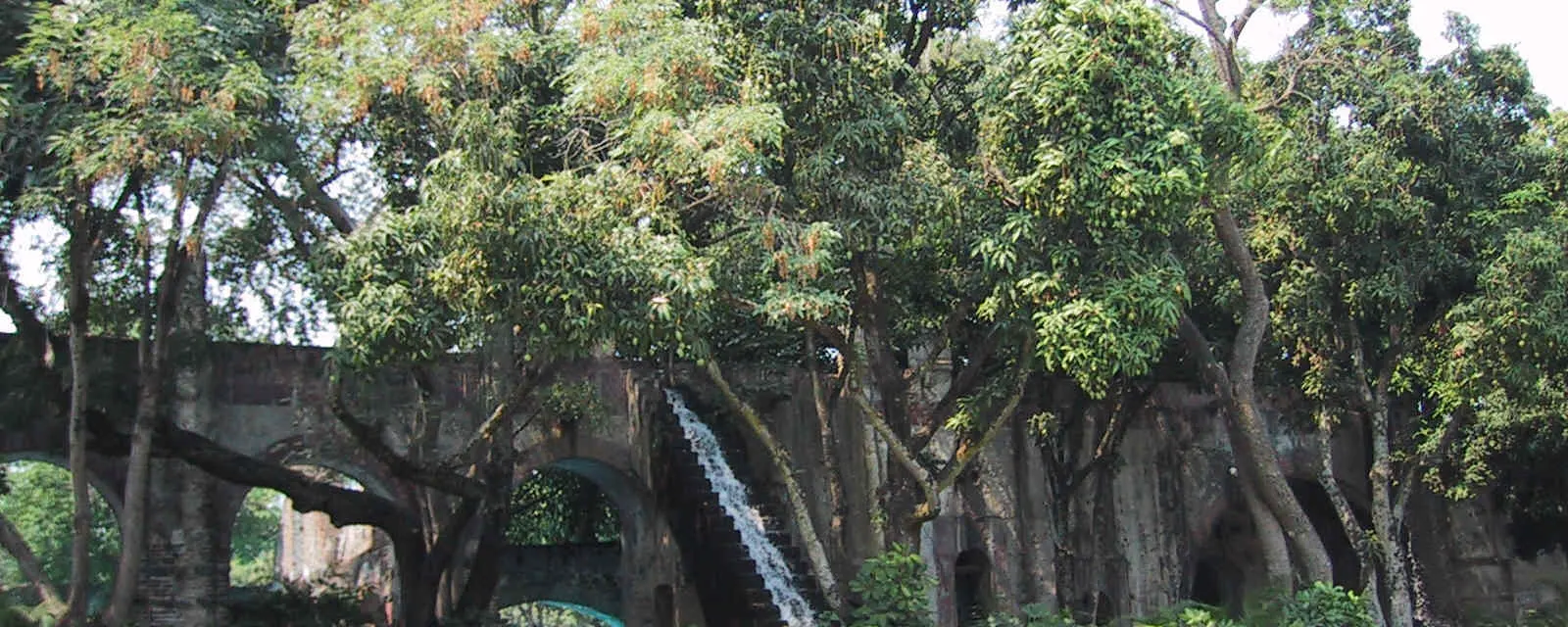 Acueducto de la hacienda de Cocoyoc con un chorro de agua cayendo entre jardines frondosos