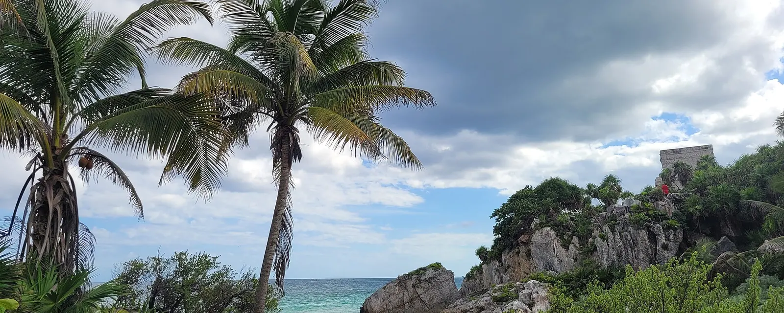 Ruinas de Tulum sobre el acantilado con palmeras y el mar Caribe al fondo