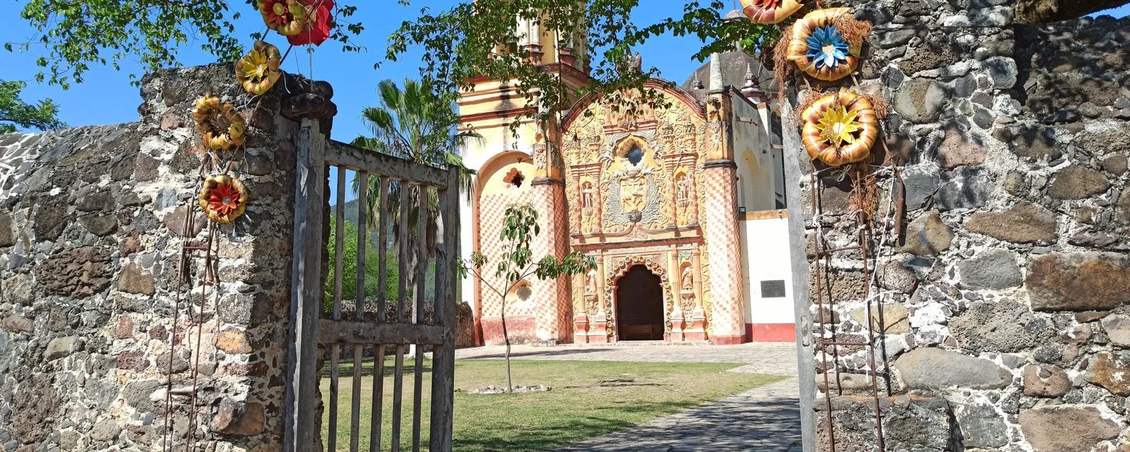 La misión de San Miguel Concá vista desde la puerta del atrio: la portada policromada de argamasa entre dos muros de piedra volcánica