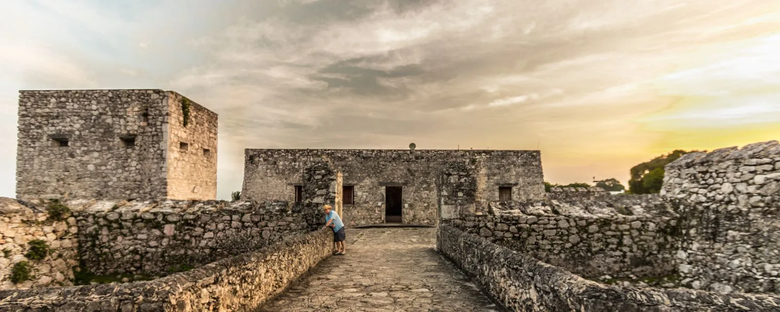 El fuerte de San Felipe en Bacalar al atardecer: sus muros de piedra y el baluarte cuadrado vistos desde el puente de acceso