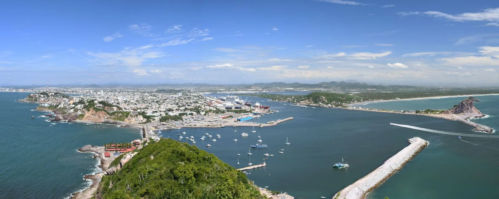 Panorámica de Mazatlán desde el cerro del Crestón: la bahía con los veleros fondeados, el puerto al centro y la ciudad extendiéndose hasta los cerros