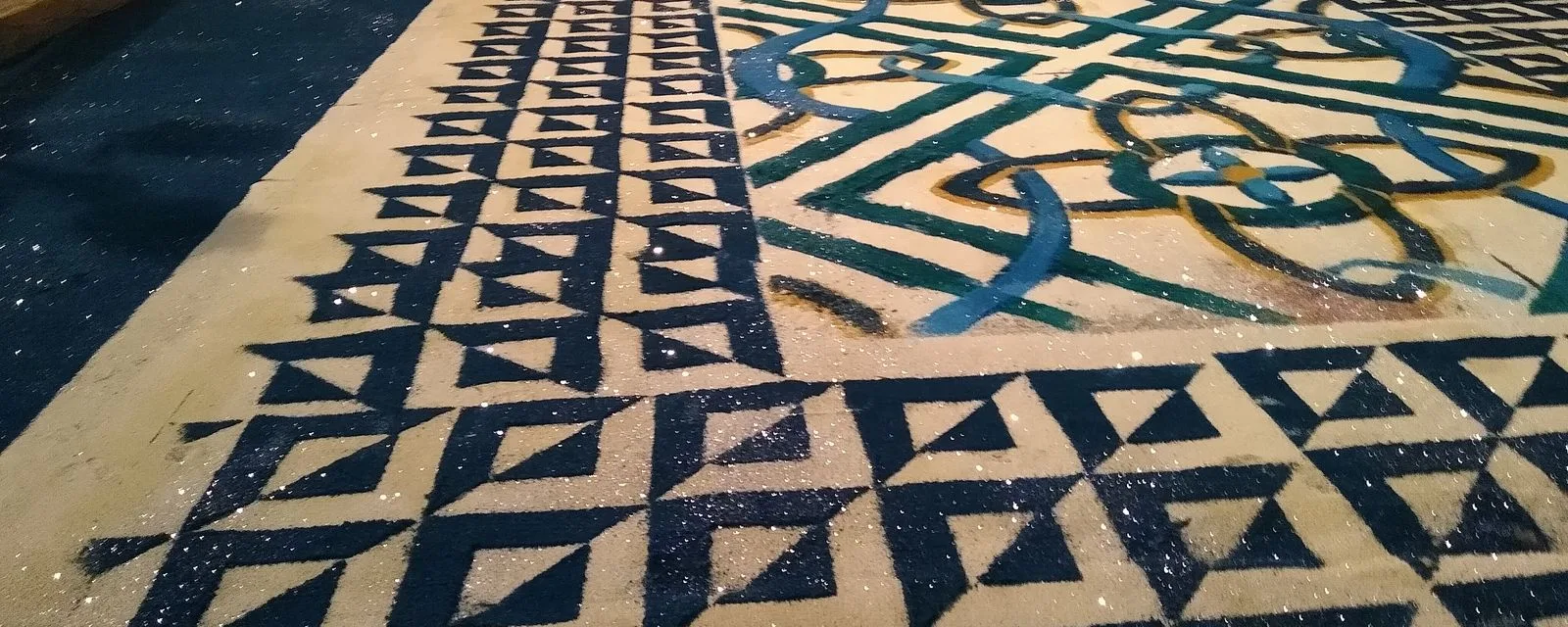 Detalle de un tapete de aserrín teñido tendido sobre la calle de Huamantla en La Noche que Nadie Duerme, con grecas azules y blancas