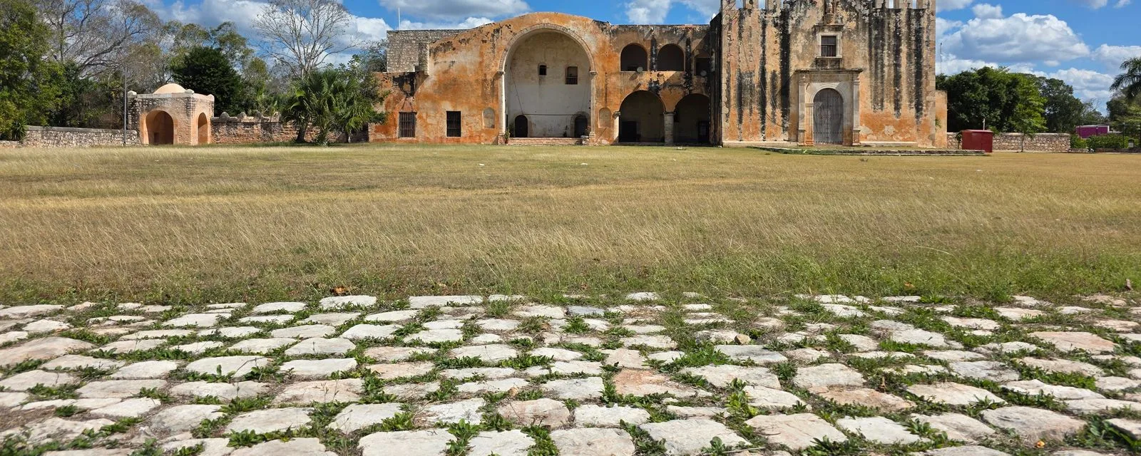 El ex convento de San Miguel Arcángel en Maní visto desde el empedrado del atrio: su gran arco de la capilla abierta y la portada de piedra dorada