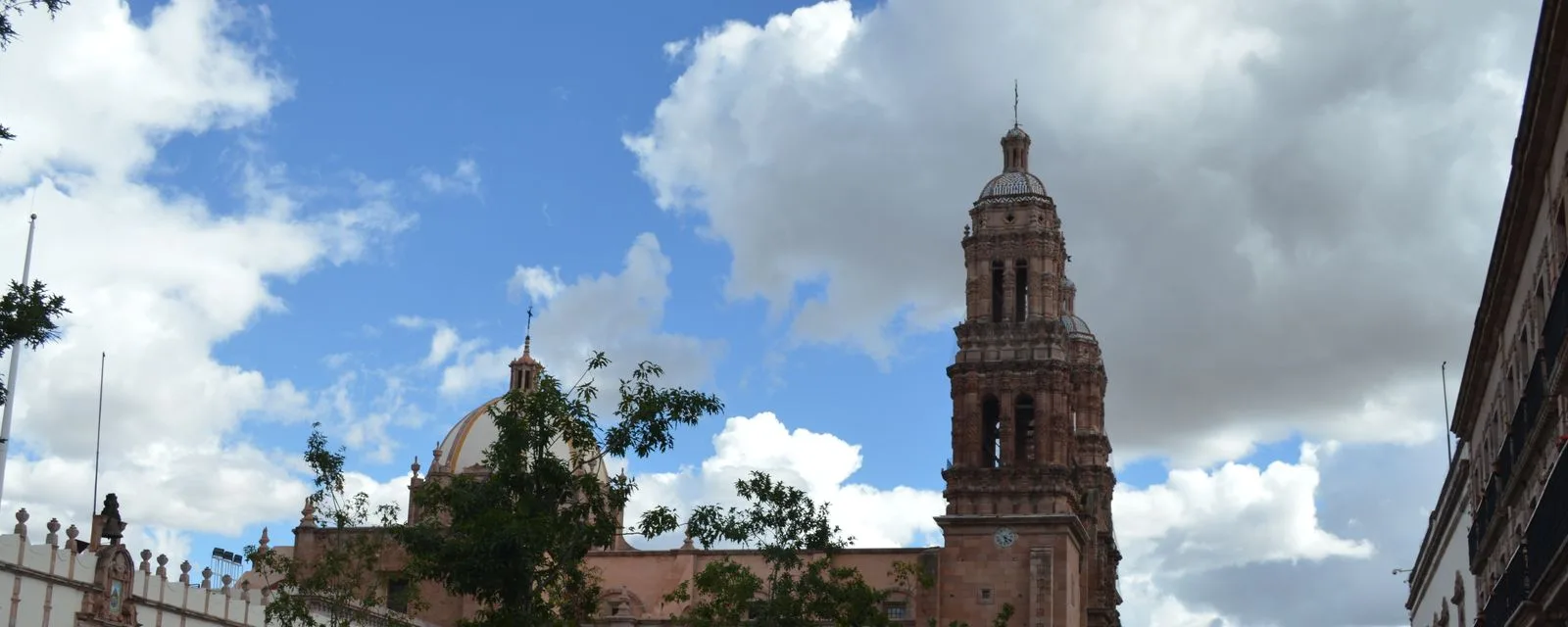 La Plaza Mayor de Zacatecas con la torre y la cúpula de la catedral de cantera rosa asomando sobre los edificios del centro histórico